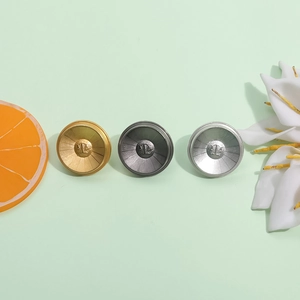 Minimalist round metal brooches in gold, gunmetal, and silver with radial texture