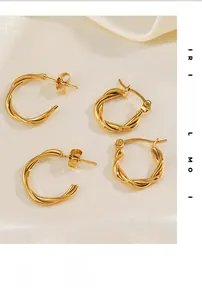 Dettaglio di orecchini a cerchio intrecciati dorati su elegante tessuto di seta bianca