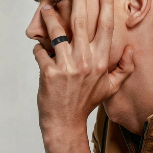 Close-up of minimalist black matte stainless steel wedding ring for men on model hand