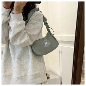 Mirror selfie showing a light green shoulder bag with ruffled strap and rabbit embroidery