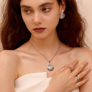 Close-up of a silver shell jewelry set including necklace, earrings, and rings on a model