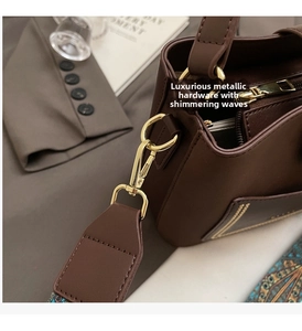 Close-up of golden metal buckle and ethnic embroidery strap on brown leather bag