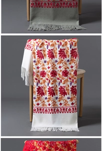 Détail d'un châle pashmina blanc avec broderie florale rouge et franges élégantes