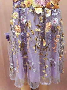 Détail de robe en tulle violet avec broderie florale 3D colorée et tiges dorées