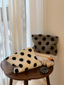 Detailed macro of plush polka dot cosmetic bags on a wooden table with home decor