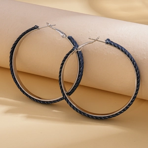 Detail of large silver hoop earrings wrapped in premium dark blue denim fabric texture