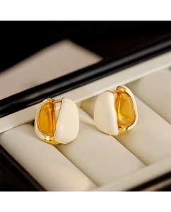 Macro view of French retro U-shaped gold earrings with creamy white enamel inlay
