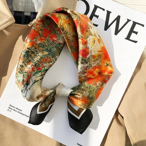 Detailed view of an oil painting style silk scarf placed on a khaki trench coat