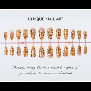 Detail of almond-shaped ginger nails with black tiger stripes and 3D pink flower charms
