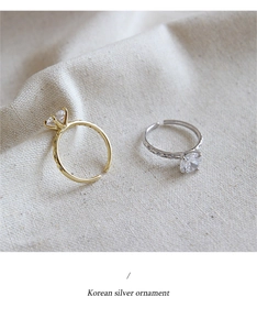 Detail view of gold and silver six-prong cubic zirconia rings on beige fabric