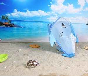 Blue shark mesh beach bag for kids on a sandy beach background with ocean view