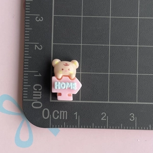 Detailed macro view of a 1.5cm resin miniature bear home sign charm for DIY crafts
