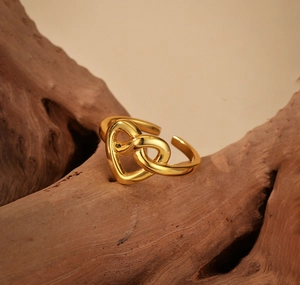 Macro view of gold intertwined double heart knot adjustable ring on rustic wood