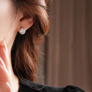 Elegant silver halo stud earrings with round cubic zirconia stones on model