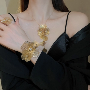 Detailed view of luxury gold hollow flower necklace set with sparkling crystals on model