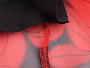 Détail de la couture et du surjet sur une robe en organza à fleurs rouges