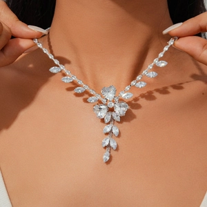 Detailed view of silver necklace with zircon heart and leaf cluster worn on neck