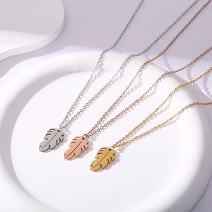 Detailed view of leaf pendants in silver, rose gold, and gold on white ceramic