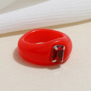Detailed close-up of a red resin ring featuring a rectangular faceted rhinestone inlay