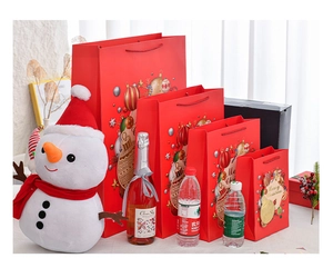 Set of four red Christmas gift bags in various sizes with festive ornaments and woven handles
