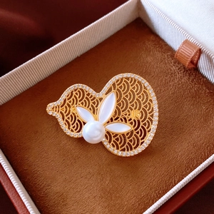 Close-up of 18K gold gourd brooch with white pearl and shell petals in jewelry box