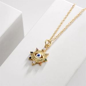 Detail of gold evil eye pendant with blue center and colorful pavé crystals on a white stand