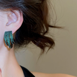 Detailed side view of multi-layer C-shape earrings with emerald green zircons