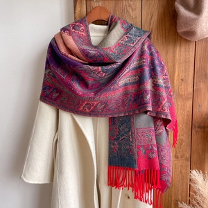 Ethnic style vintage paisley jacquard scarf with red tassels hanging on a hanger