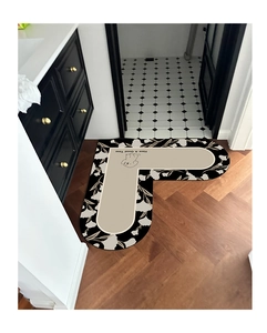 Close-up of U-shaped bath mat with floral patterns and 'Have A Good Time' text on wood floor