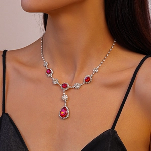 Gros plan d'un collier en Y argenté avec pierres rouges et cristaux sur un mannequin