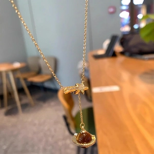 Detailed close-up of a golden planet pendant necklace with zircon star and tiger eye stone