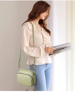Fashionable green crossbody bag with quilted leather design worn by a female model