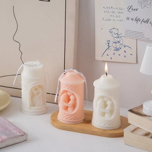 Detail of lit pillar candles with romantic couple relief and elegant grid texture