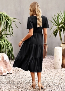 Back view of a black short sleeve dress featuring a gathered waist and tiered skirt