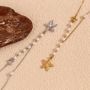 Detail of gold and silver starfish necklaces with pearls on a textured background