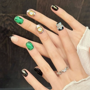 Short hand-sculpted press-on nails featuring green GG patterns and silver butterfly ring