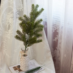 Artificial pine branches in a woven glass vase for Christmas home decoration greenery