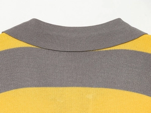Detail shot of a knitted polo shirt featuring grey ribbed collar and yellow striped pattern