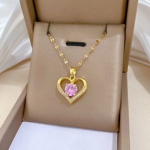 Detail of gold heart pendant with pink gemstone and zircon accents on fine chain