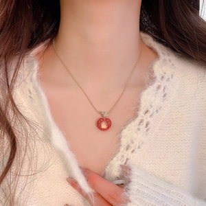Close-up of a sweet red apple pendant necklace with zircon and resin on a model