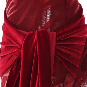 Dettaglio del nodo in velluto rosso con tessuto a rete trasparente su un abito