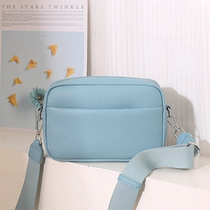 Detail of light blue lychee pattern PU leather crossbody bag with wide woven strap