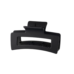 Macro detail of large matte black rectangular hair claw clip with embossed logo