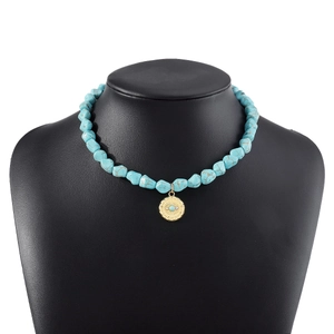 Detail of bohemian turquoise beaded necklace with golden evil eye pendant on a black bust