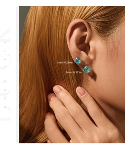 Close-up of 7mm and 8mm light blue gemstone stud earrings in gold claw settings