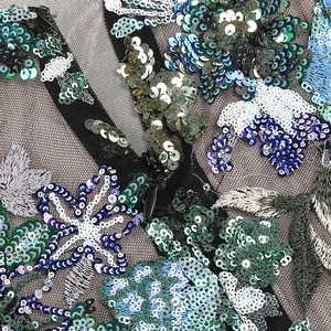 Vue détaillée des paillettes et broderies sur tissu en maille noire avec fermeture éclair