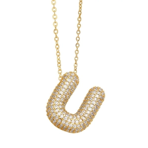 Macro detail of gold bubble letter U necklace pendant encrusted with sparkling crystals