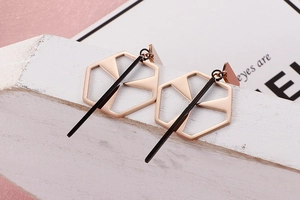 Macro shot of geometric hollow hexagon earrings in rose gold with black bar accents