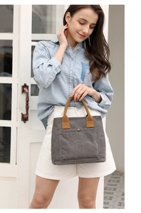 Detailed view of casual canvas tote bag with brown handles and front pocket, model showcase.
