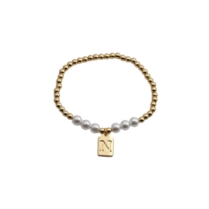 Detail of beaded bracelet featuring gold metal spheres, white pearls, and a letter N charm